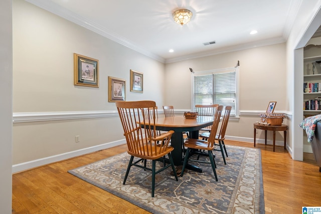 dining room with crown molding and light wood-type flooring