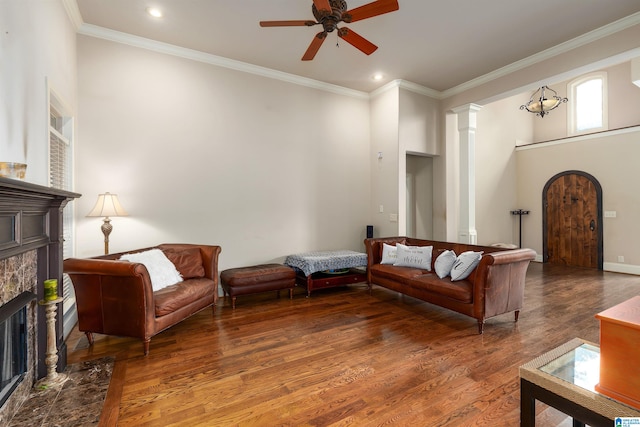 living room featuring crown molding, dark hardwood / wood-style floors, ceiling fan with notable chandelier, and decorative columns