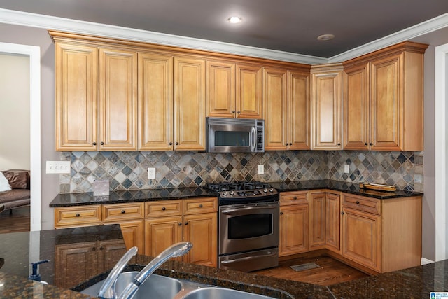 kitchen with decorative backsplash, appliances with stainless steel finishes, ornamental molding, dark stone countertops, and dark hardwood / wood-style floors