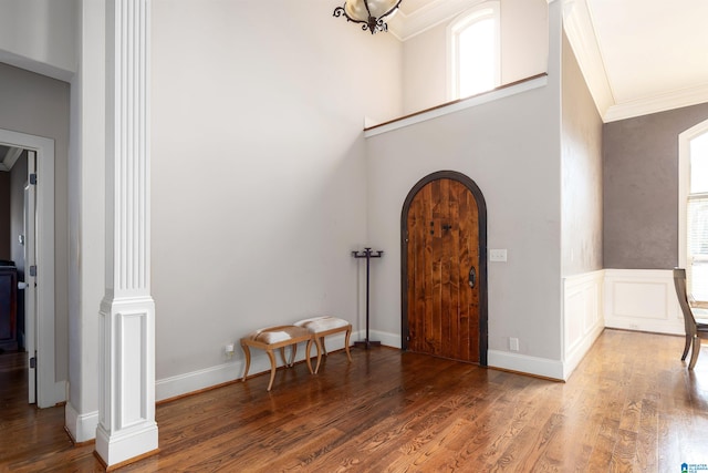 foyer entrance featuring crown molding, decorative columns, and hardwood / wood-style floors