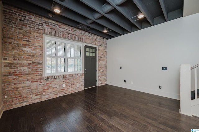 interior space with brick wall, a towering ceiling, and hardwood / wood-style floors