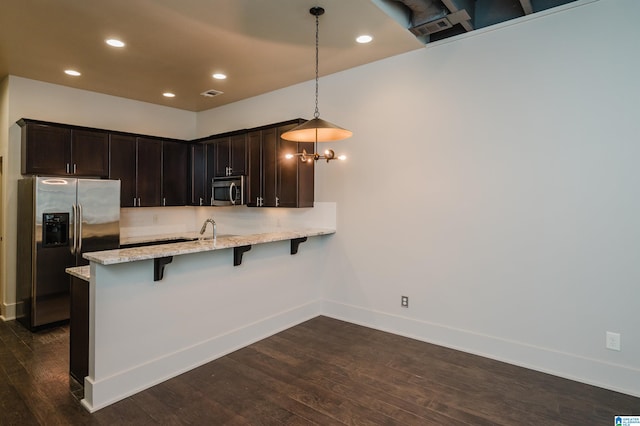 kitchen with a kitchen breakfast bar, decorative light fixtures, stainless steel appliances, and dark hardwood / wood-style flooring