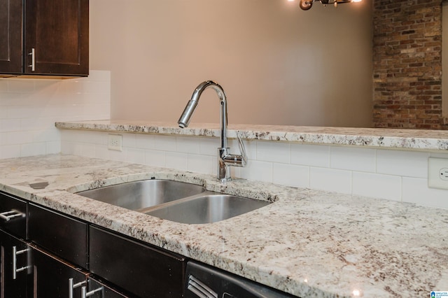 kitchen with light stone countertops, sink, decorative backsplash, and dark brown cabinets