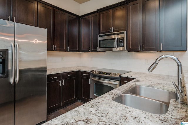 kitchen with decorative backsplash, dark wood-type flooring, sink, appliances with stainless steel finishes, and light stone counters