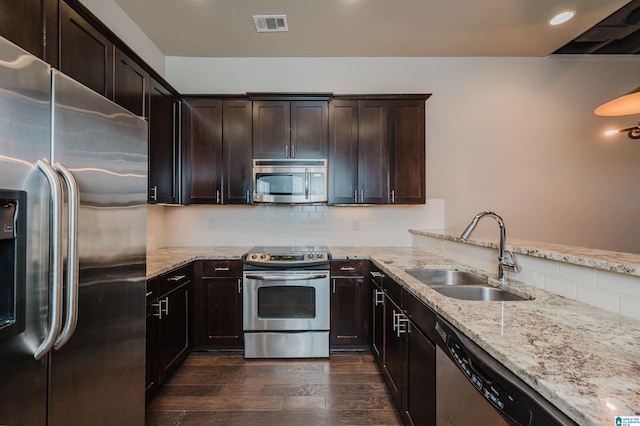 kitchen with light stone countertops, appliances with stainless steel finishes, sink, decorative backsplash, and dark hardwood / wood-style floors