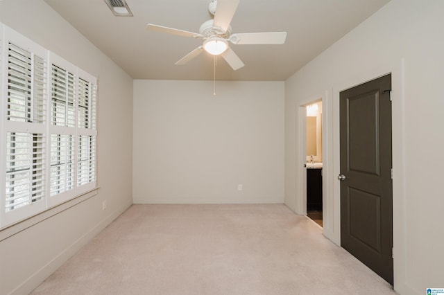 unfurnished bedroom featuring connected bathroom, ceiling fan, and light colored carpet