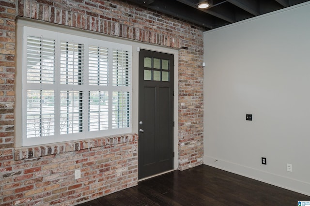 foyer featuring dark hardwood / wood-style flooring, brick wall, and plenty of natural light