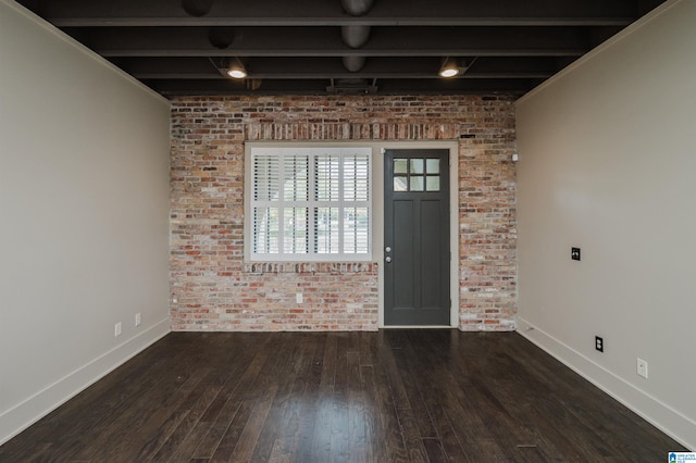 foyer with brick wall, beamed ceiling, and dark hardwood / wood-style floors