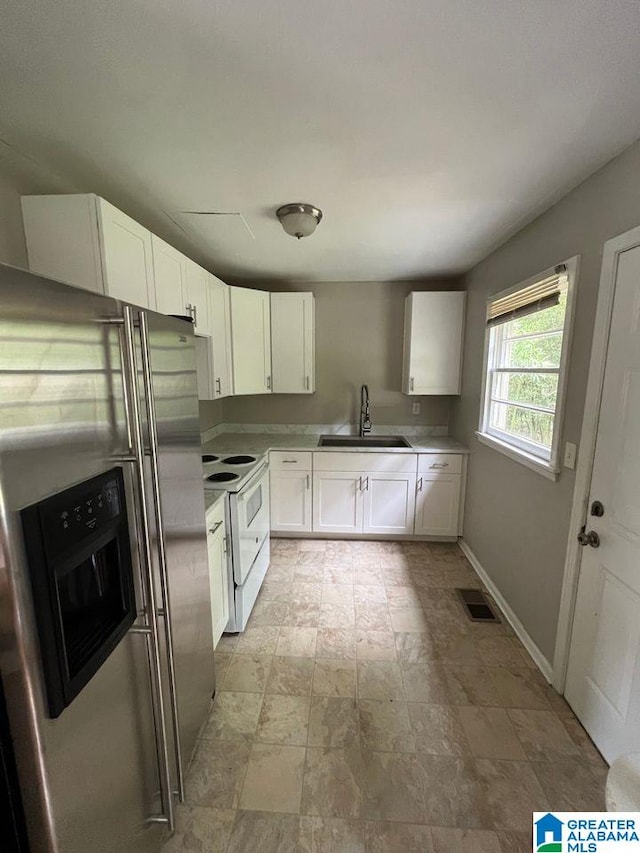 kitchen featuring sink, stainless steel fridge with ice dispenser, electric range, and white cabinets