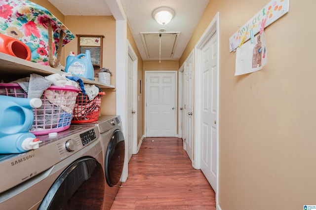 clothes washing area with washing machine and dryer, attic access, wood finished floors, and baseboards