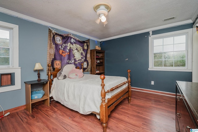 bedroom with ornamental molding, wood finished floors, multiple windows, a textured ceiling, and baseboards