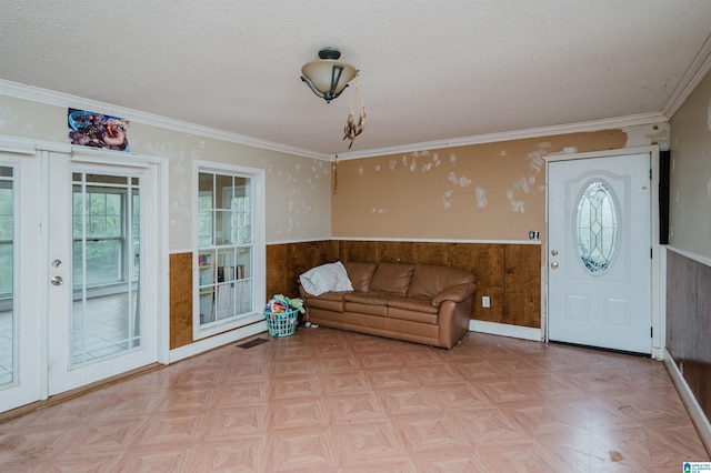 living room with wainscoting, a textured ceiling, ornamental molding, and french doors
