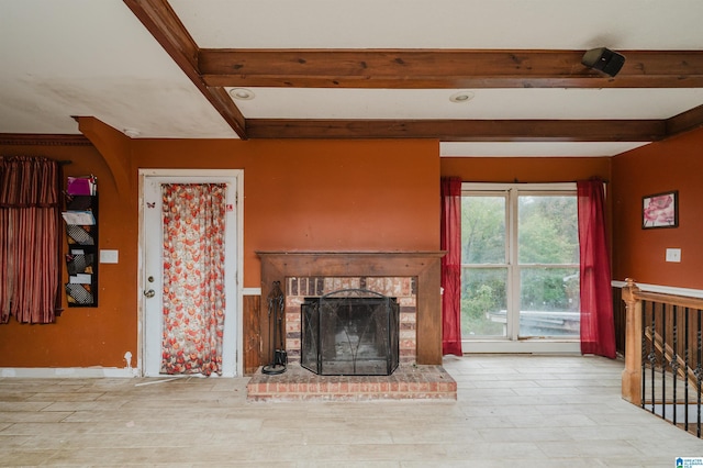 unfurnished living room featuring beam ceiling, a fireplace, and wood finished floors