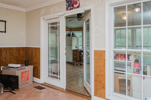 interior space with ornamental molding, parquet floors, wooden walls, and ceiling fan