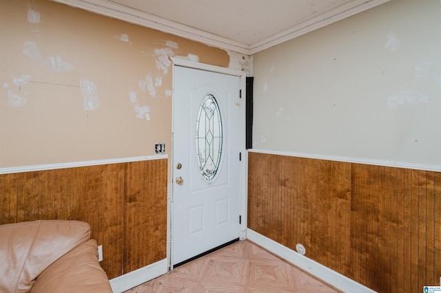 foyer with crown molding, light parquet flooring, and wood walls