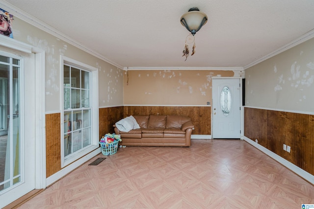 unfurnished living room featuring ornamental molding, wood walls, and light parquet flooring