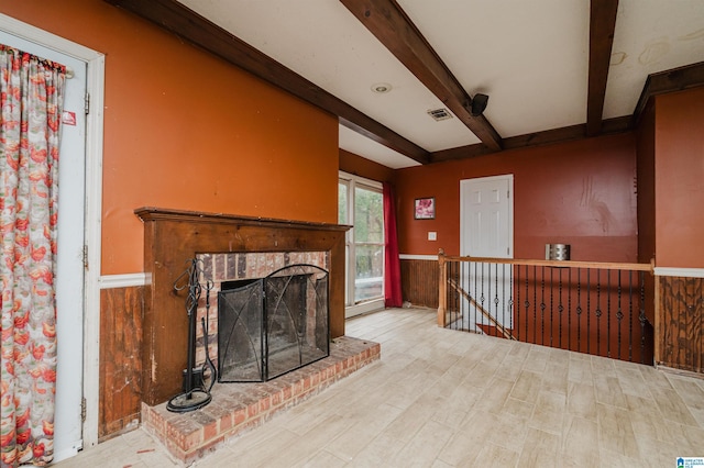 unfurnished living room with beam ceiling, a fireplace, wood finished floors, and a wainscoted wall