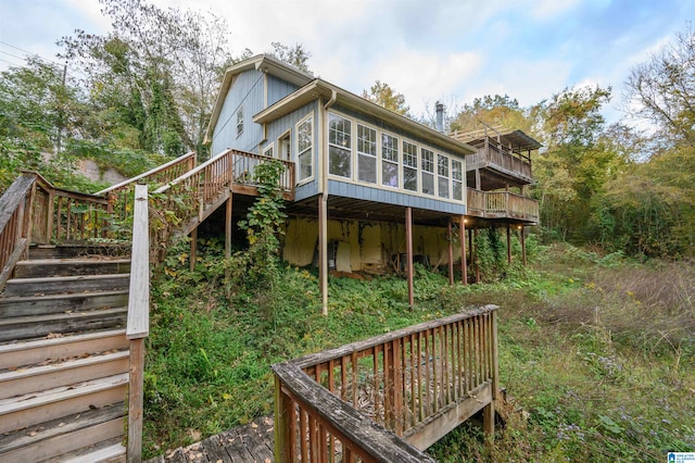 back of property featuring a wooden deck and a sunroom