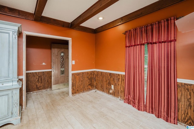 unfurnished room with beamed ceiling, light hardwood / wood-style floors, and wood walls