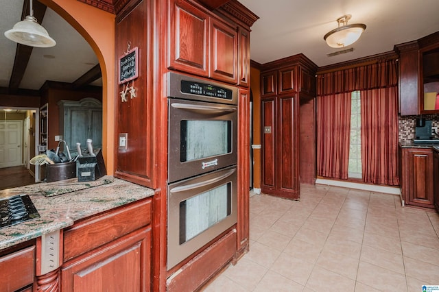kitchen featuring double oven, arched walkways, light stone countertops, decorative light fixtures, and light tile patterned floors