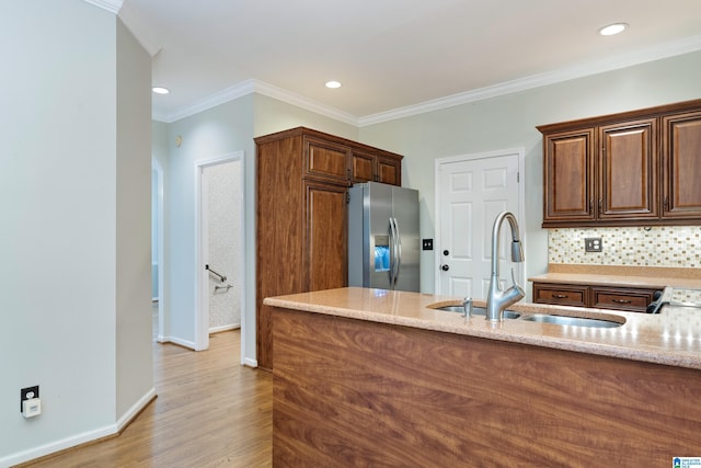 kitchen featuring sink, backsplash, stainless steel fridge, light wood-type flooring, and ornamental molding