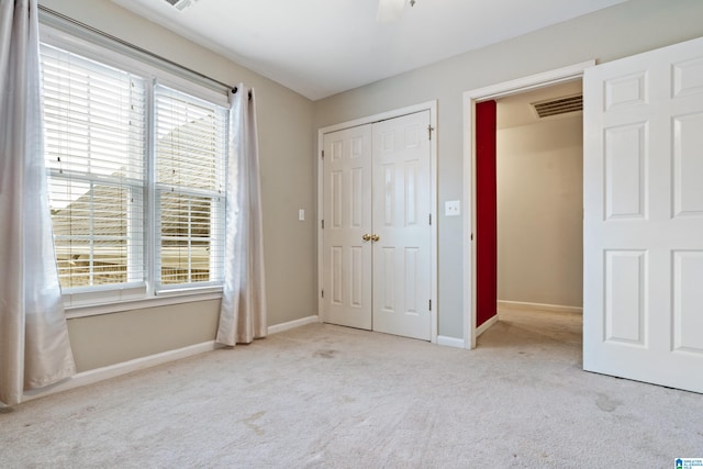 unfurnished bedroom featuring a closet, light colored carpet, and multiple windows