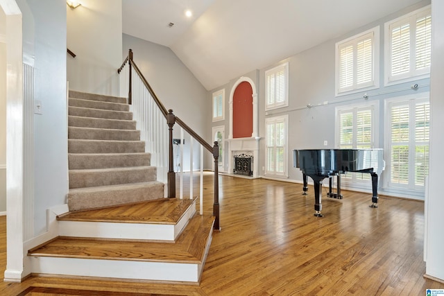 stairway with wood-type flooring and high vaulted ceiling