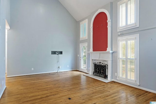 unfurnished living room with hardwood / wood-style floors, high vaulted ceiling, and plenty of natural light