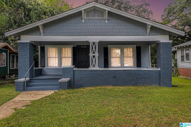 bungalow-style house with covered porch and a lawn