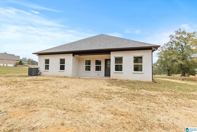 rear view of property featuring a lawn and central AC unit