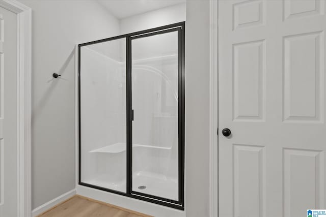 bathroom with an enclosed shower and hardwood / wood-style floors