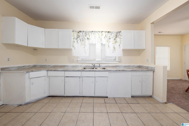 kitchen with white cabinets, light colored carpet, and sink