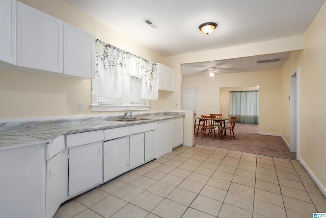 kitchen featuring ceiling fan, sink, light colored carpet, and white cabinets