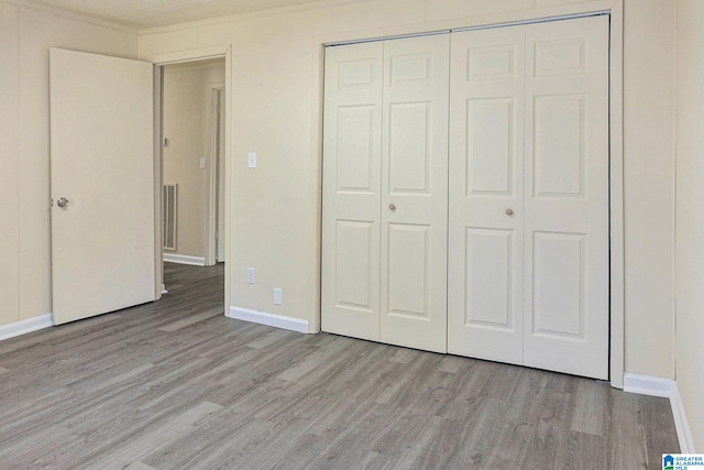 unfurnished bedroom with ornamental molding, light hardwood / wood-style flooring, and a closet