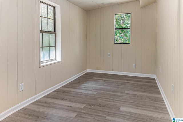 spare room featuring a healthy amount of sunlight, hardwood / wood-style flooring, and wooden walls