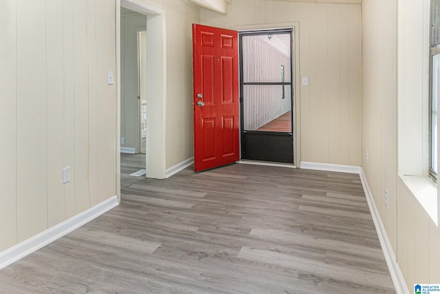 entryway with light hardwood / wood-style floors and wood walls