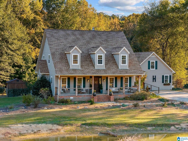 cape cod-style house with a front yard and a porch