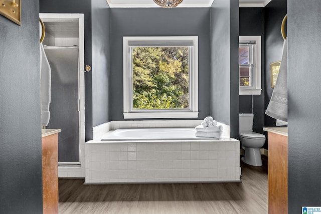 bathroom featuring toilet, tiled bath, crown molding, and hardwood / wood-style floors