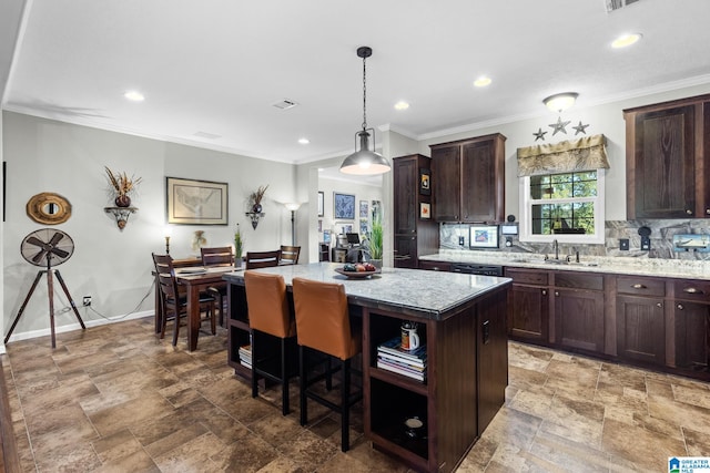 kitchen featuring a center island, light stone countertops, pendant lighting, dark brown cabinetry, and sink