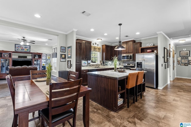 kitchen with stainless steel appliances, crown molding, a kitchen island, sink, and decorative light fixtures