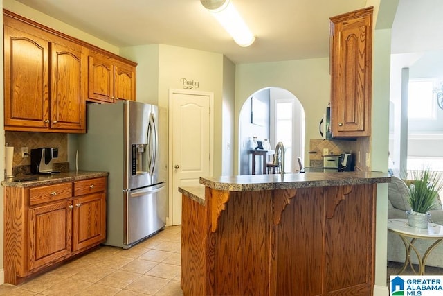 kitchen featuring appliances with stainless steel finishes, kitchen peninsula, tasteful backsplash, and plenty of natural light