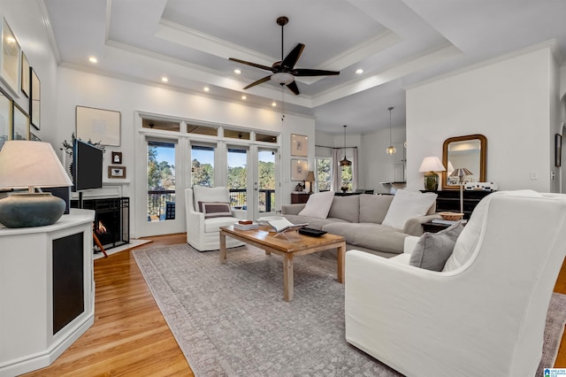 living room with french doors, ornamental molding, a tray ceiling, ceiling fan, and light hardwood / wood-style floors