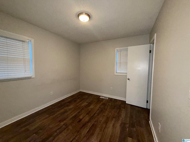 spare room with dark hardwood / wood-style floors and a textured ceiling