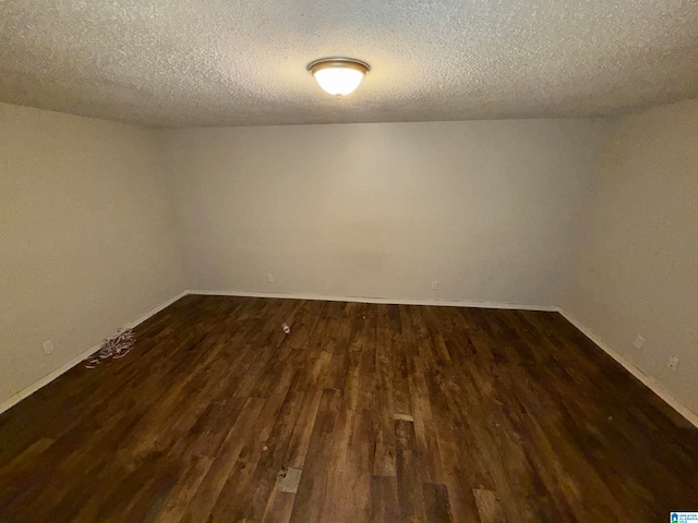 unfurnished room featuring dark wood-type flooring and a textured ceiling