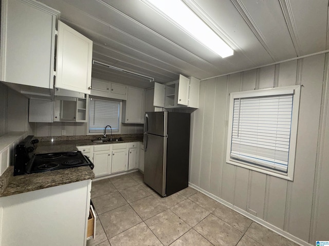 kitchen with black / electric stove, sink, stainless steel refrigerator, and white cabinets