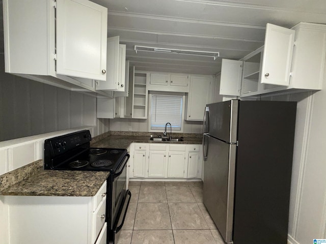 kitchen featuring stainless steel refrigerator, light tile patterned floors, black electric range oven, sink, and white cabinets