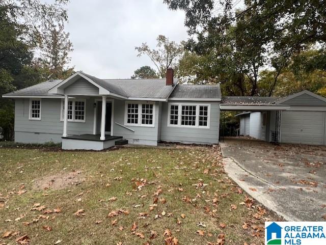 single story home featuring a front yard, an outbuilding, a garage, and a carport