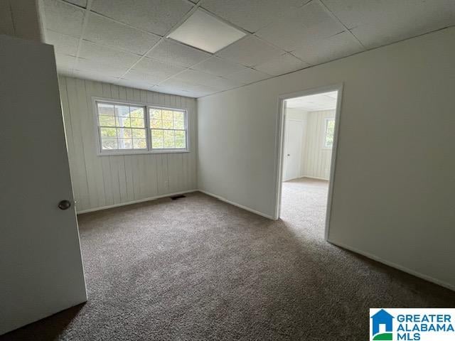 empty room with a drop ceiling and carpet