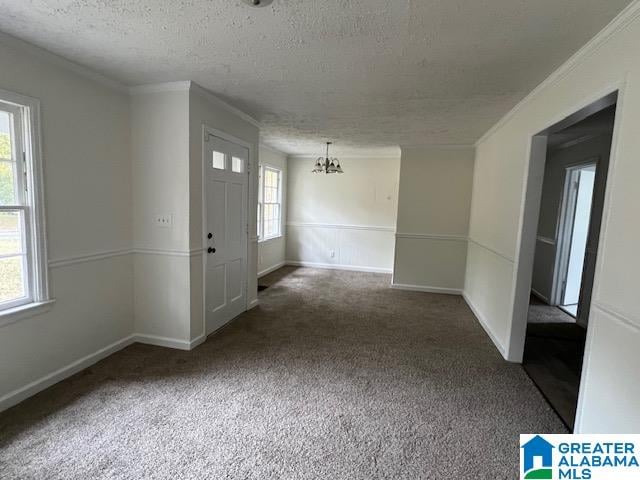 foyer entrance featuring a healthy amount of sunlight, an inviting chandelier, and dark colored carpet