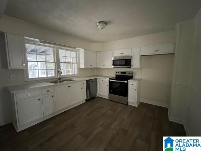 kitchen featuring appliances with stainless steel finishes, a textured ceiling, white cabinetry, dark hardwood / wood-style floors, and sink